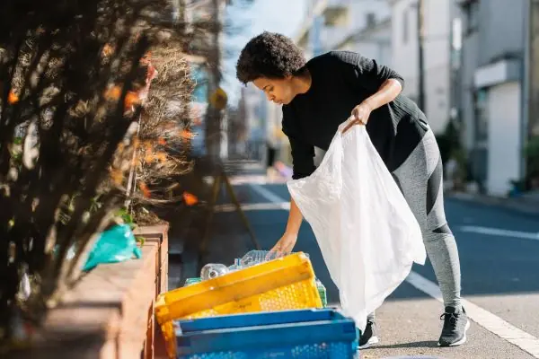 women separating yard waste and recycling bottle