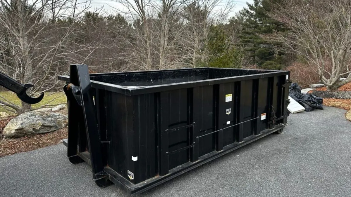 yard black color dumpster on the side of driveway