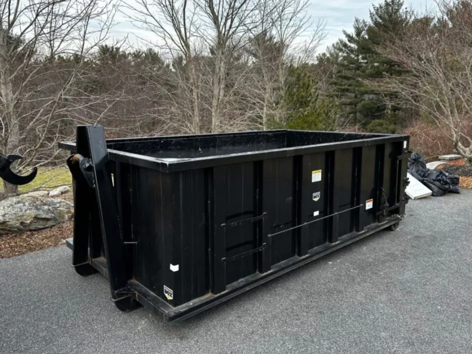 yard black color dumpster on the side of driveway