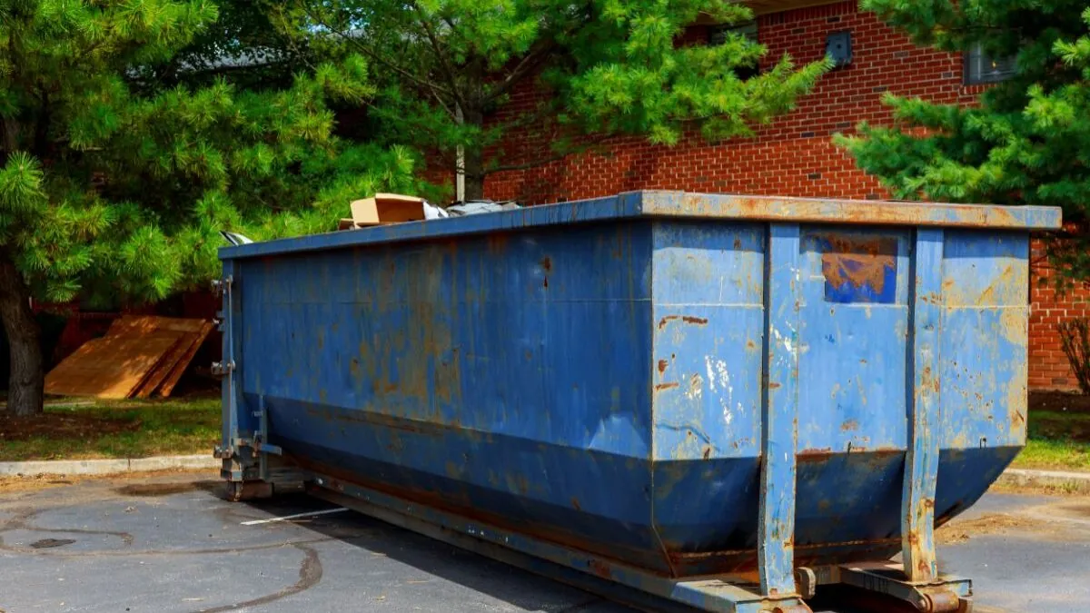 a blue yard dumpster being full of garbage