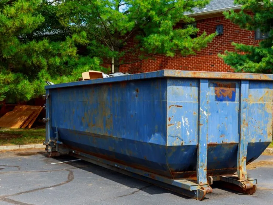 a blue yard dumpster being full of garbage